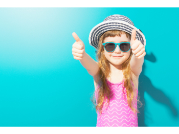 girl in hat and sunglasses giving two thumbs up