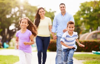 two children and two parents happily walk down a sidewalk