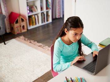 A child works intently on a laptop