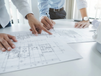 two people pointing at blueprint plans
