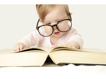 baby in glasses looking at book