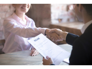 man and woman shaking hands while man holds resume