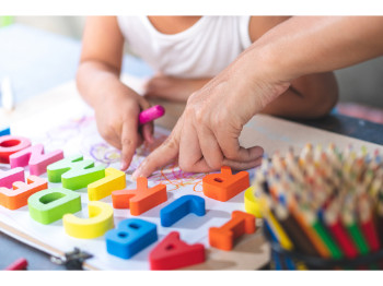 child and adult hands using magnetic letters