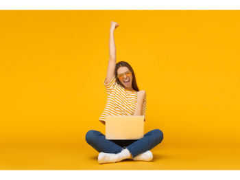 girl sitting with a computer cheering with arm in the air