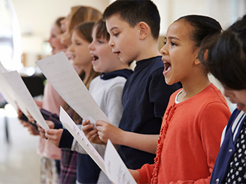 A row of kids singing from music sheets