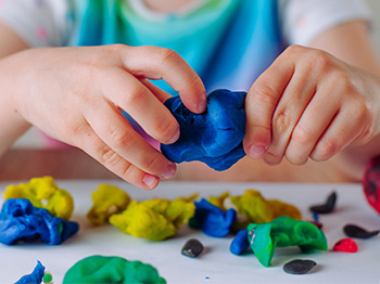 A child playing with colourful dough.