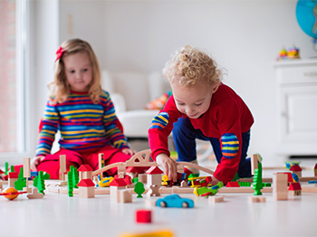 Two children playing with wooden blocks and toys.