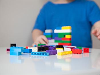 Child with blue shirt playing Lego