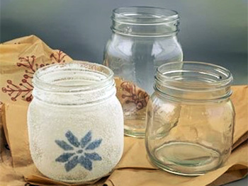 Three small jars. Two are empty and one has a frosted look with a star design.