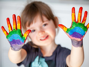 Child with rainbow messy fingers