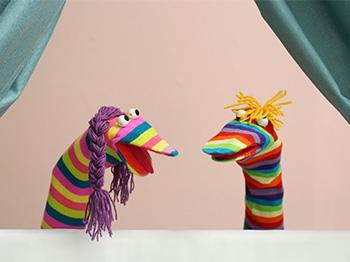 Two rainbow sock puppets talking
