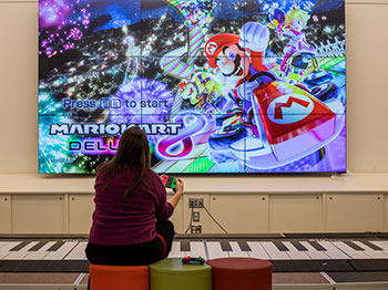 Woman playing Mario Kart on a big screen