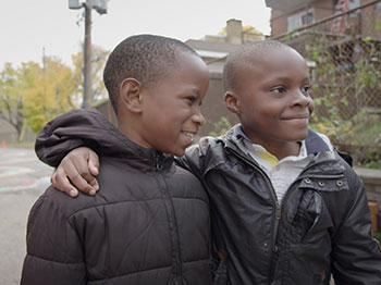 Two young smiling boys with their arms around each other.