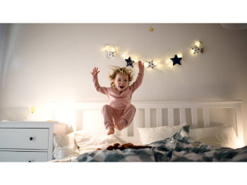 A toddler in pyjamas bounding on a bed.