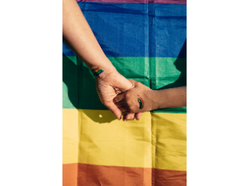 hands in front of a pride flag