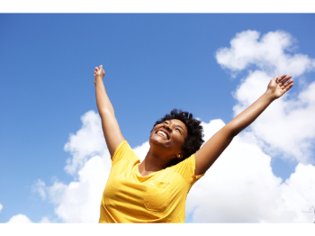 Happy person with arms outstretched against sky background