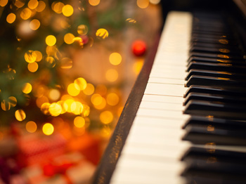 A piano with festival lights blurred in the background.