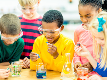 Children performing a science experiement with safety glasses and beakers.