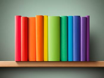 A series of rainbow-coloured book spines on a wooden bookshelf.