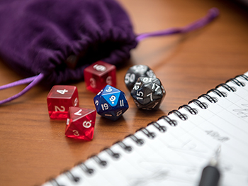 Dungeons and Dragons dice and gameboard on a table.