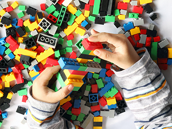 A child building with many colourful pieces of LEGO bricks.
