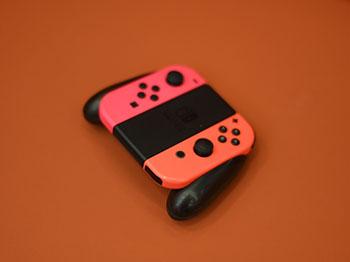 Pink and orange Nintendo Switch controller on a plain orange background.