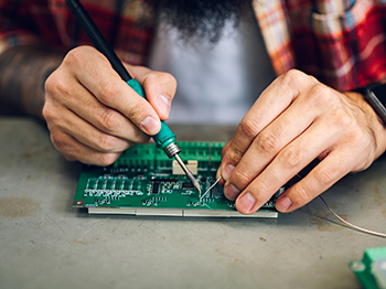 An adult soldering a circuit board.