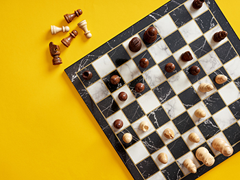 A chess board and with peices on a yellow background.
