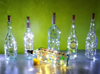 A series of bottles with light strings glowing inside infront of a green background.