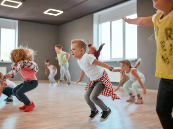 A group of children jumping and dancing in a dance studio.