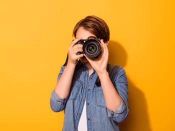 A photograph of a holding a camera in front of their face. 