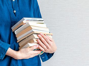 Person holds a stack of books