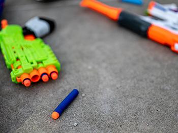 Nerf blasters and darts scattared on floor.