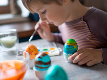 A child painting hard-boiled eggs.
