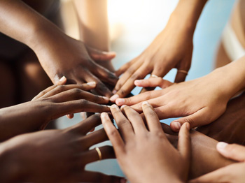 A group of people touching hands together in a circle.