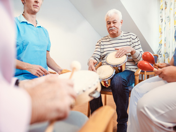 Seniors in nursing home making music with rhythm instruments.