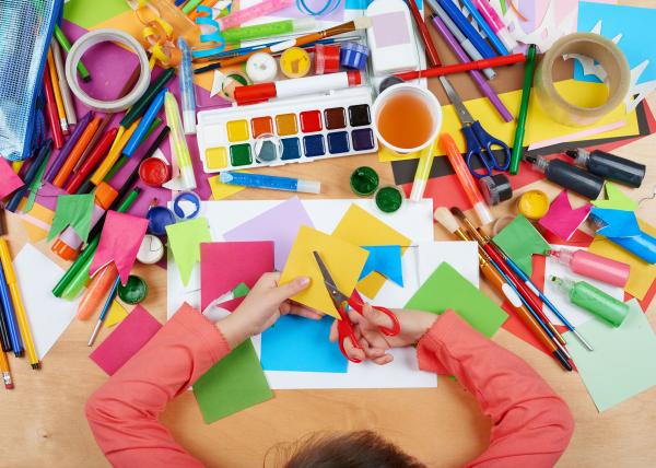 A child sits in front of a table filled with art supplies.