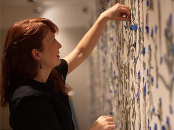 A  photograph of Amanda McCavour installing work in a gallery