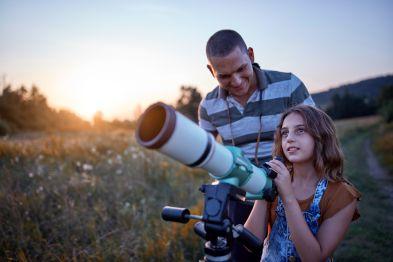 Father and Daughter using a telescope to look at the night sky