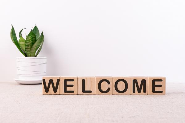 The word "WELCOME" spelled out on wooden blocks next to a potted plant.
