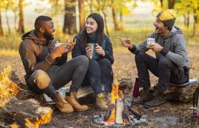 Three people sitting around a campfire talking