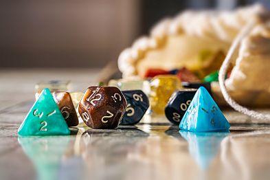 Various dice on a table with bag in the background