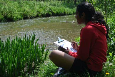 Teenager sithttps://ideaexchange.libnet.info/images/events/ideaexchange/EcoSparks2.jpgting by a river with a clipboard