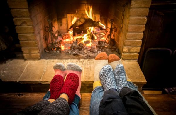Four pairs of socked feet in front of a fireplace