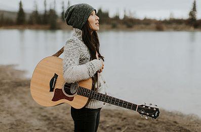 Ginalina on the beach with her guitar