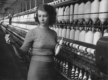 A black and white photo of a young woman holding a spool of thread