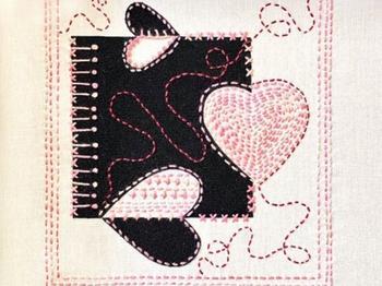 A black and white quilted square with pink stitching creating wavy lines and heart outlines. 