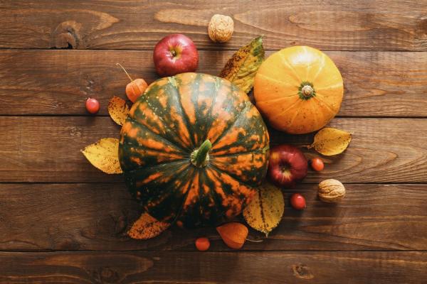 Colourful pumpkins and gourds on a table with apples and fall leaves