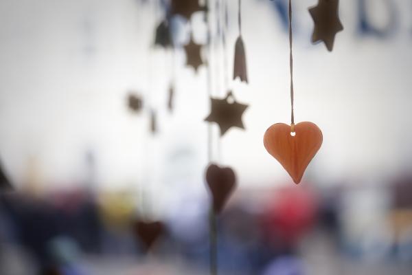 Paper cut outs of hearts and stars hang from string on a blurry white background.